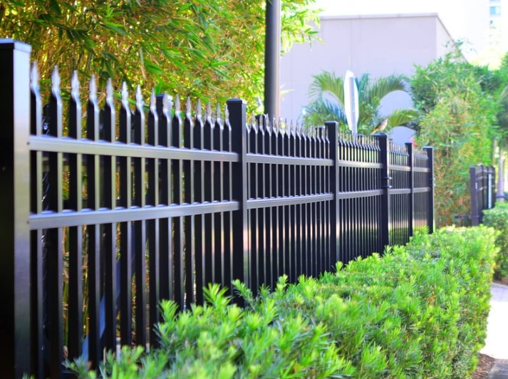 Black aluminum commercial fence running along landscaped greenery at a Monmouth County, New Jersey business property, providing clean lines, security, and curb appeal.