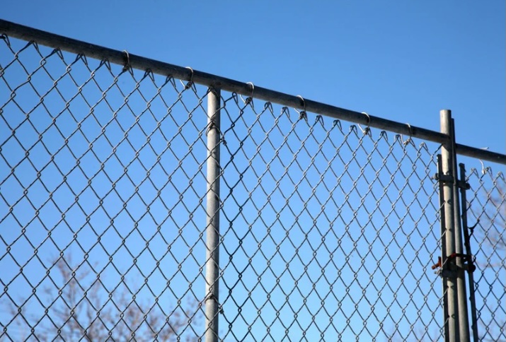 Galvanized chain link fence with a secure gate section against a clear sky at a commercial property in Ocean County, New Jersey.